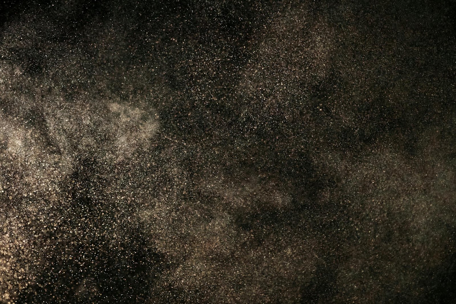 A captivating view of dust particles floating against a dark backdrop, creating a celestial feel.