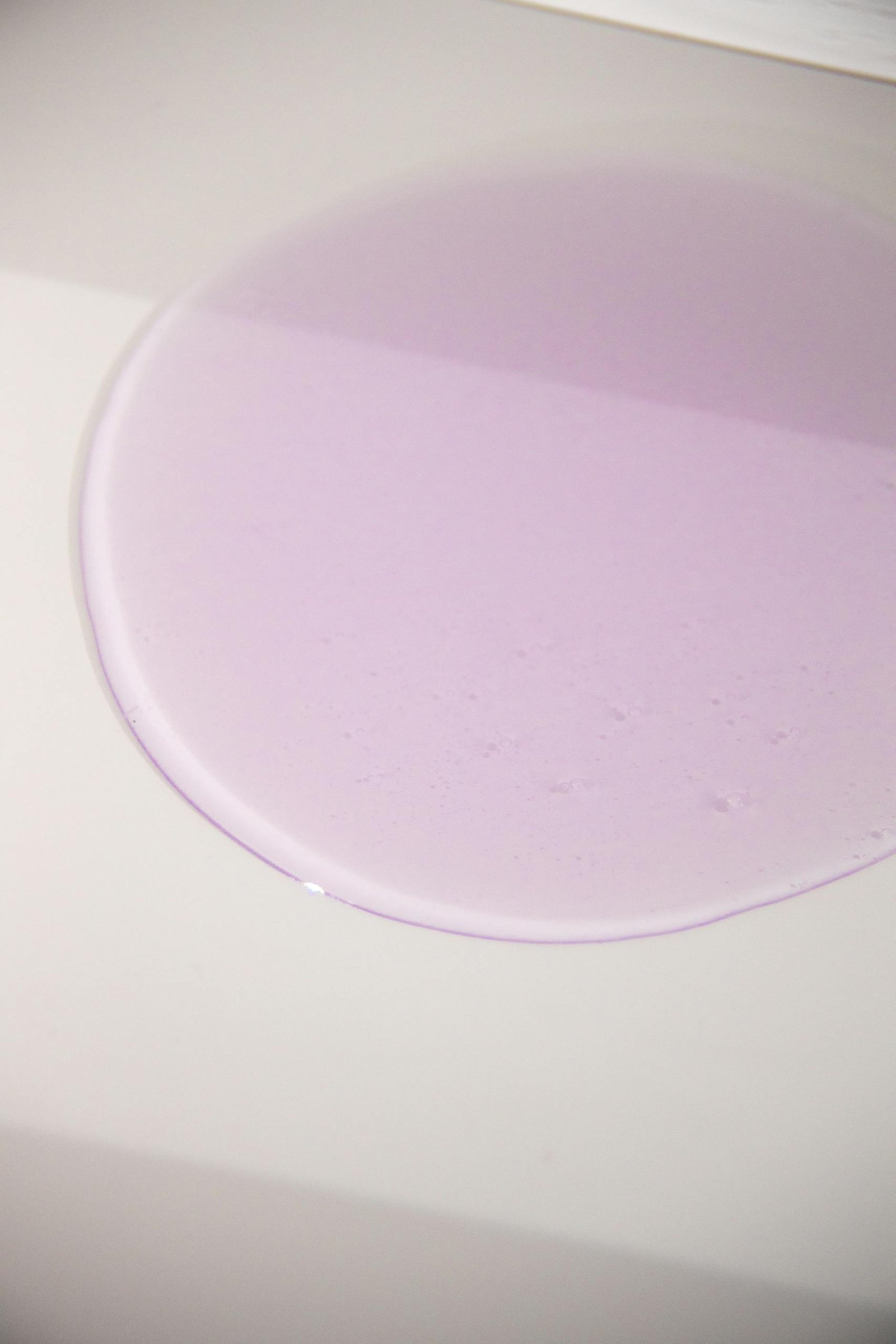 Abstract image of purple liquid forming a smooth circle on a white surface.
