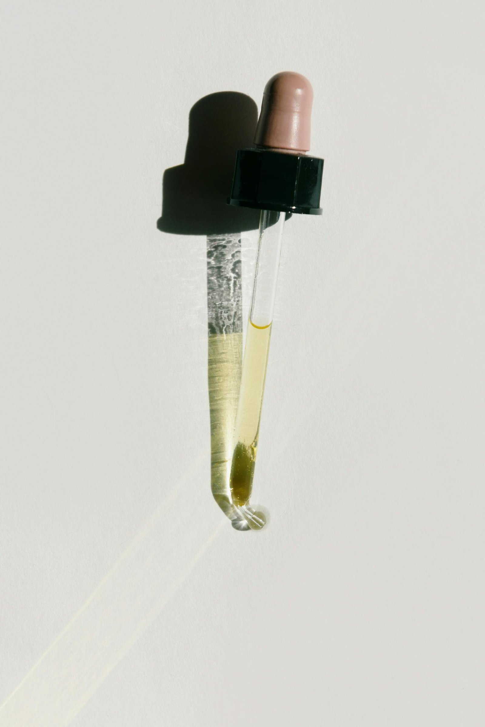 Close-up of a dropper casting a shadow, highlighting minimal design and natural oil.