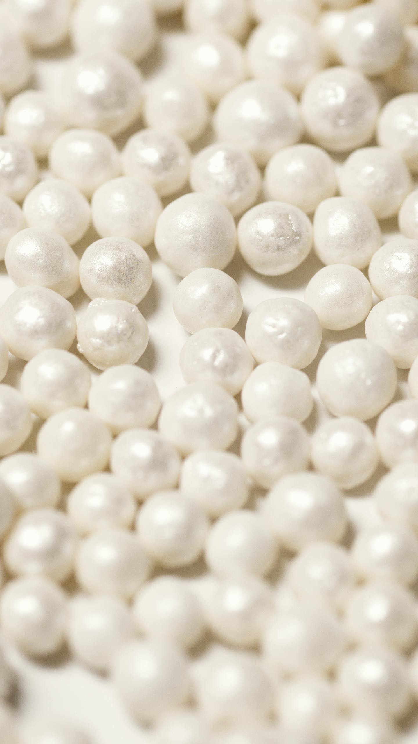 Close-up of scattered white pearls creating a luxurious, abstract texture.