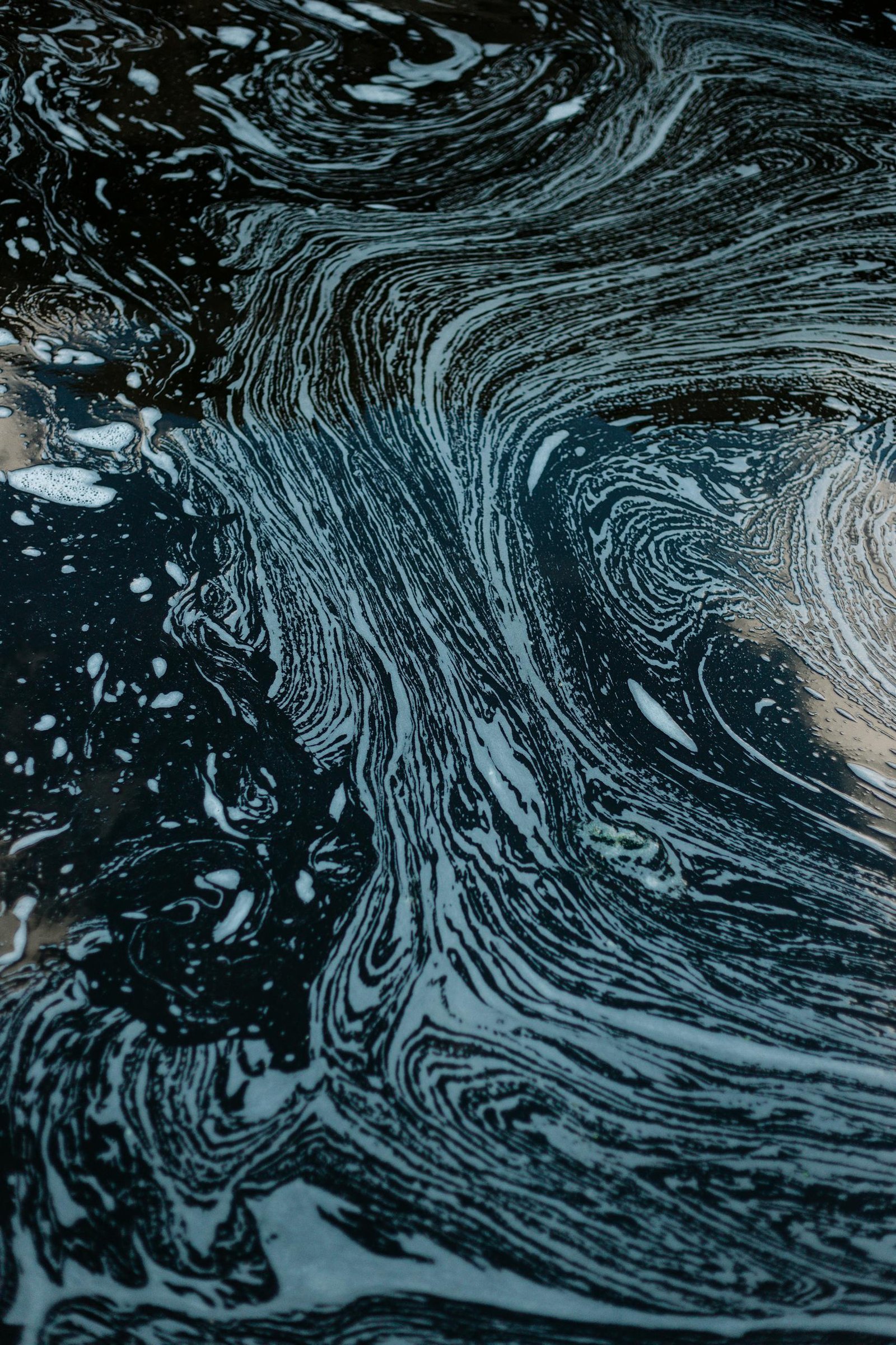 Dynamic abstract art capturing swirling liquid patterns and textures in contrasting tones.