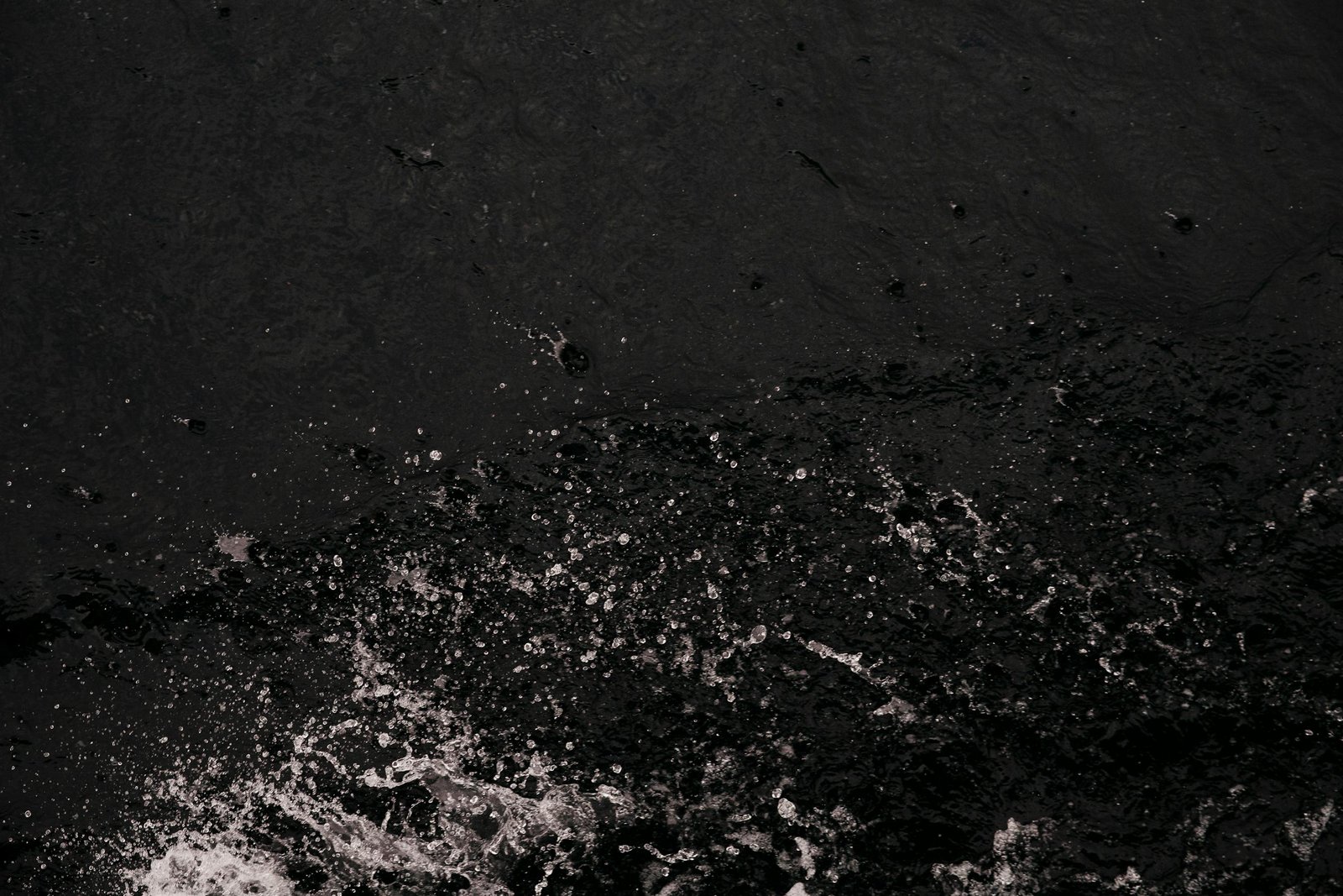 Dynamic water splash against a dark, textured background creates a striking abstract impression.