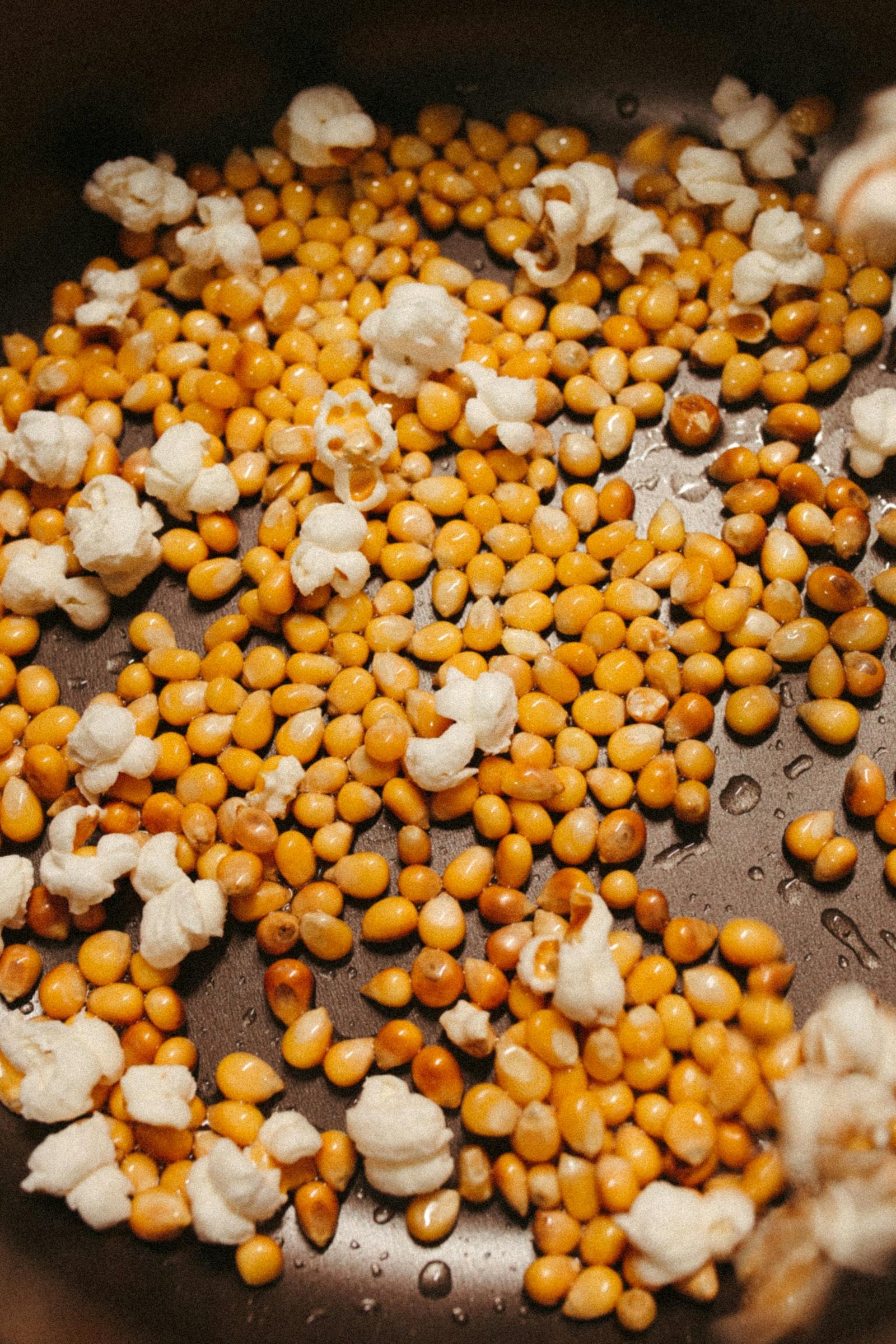 High angle view of popcorn kernels in a frying pan, some popcorn popped.
