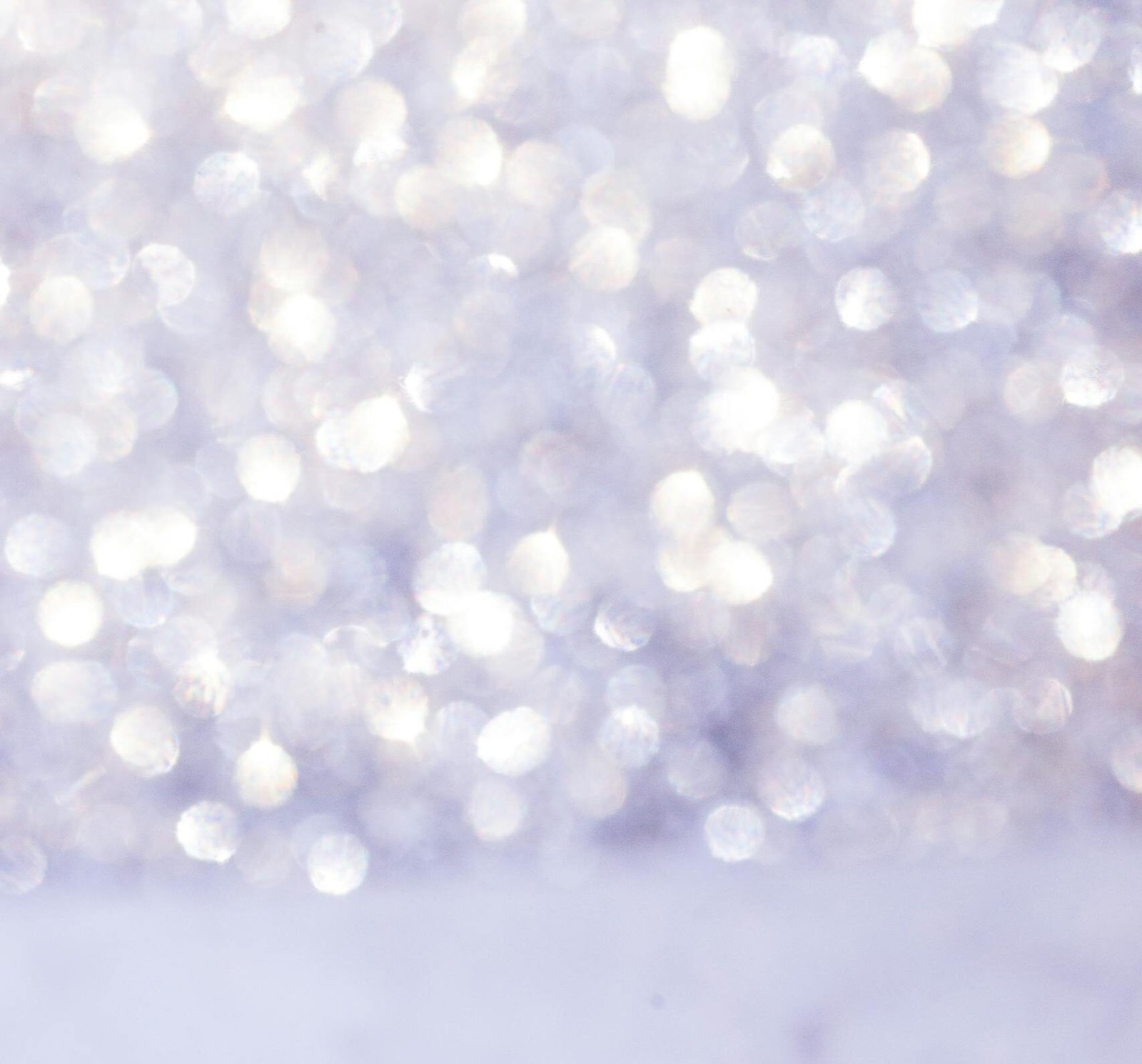 Close-up of a sparkling diamond engagement ring on a marble surface with bokeh background.